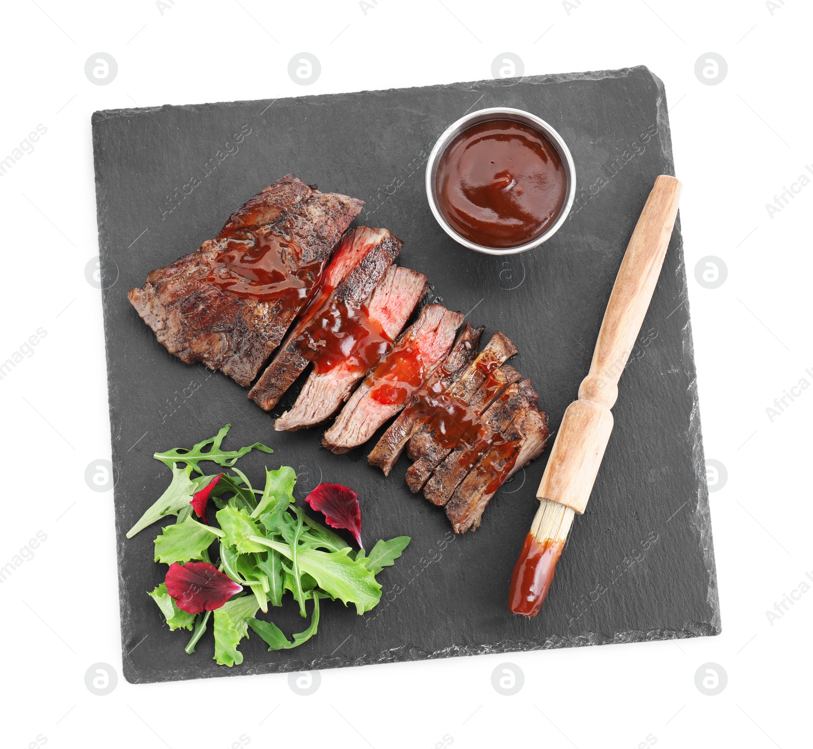 Photo of Pieces of delicious roasted beef meat with sauce and greens isolated on white, top view