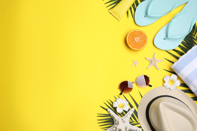 Beach accessories on yellow background, flat lay. Space for text