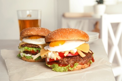 Photo of Tasty burgers with fried egg on parchment