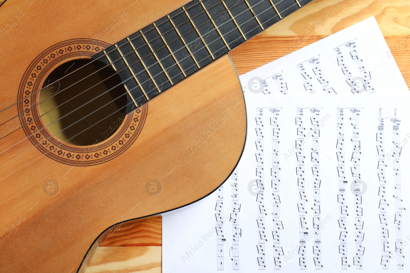 Photo of Beautiful classical guitar and music sheets on wooden background, top view