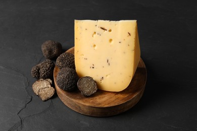 Wooden board with delicious cheese and fresh truffles on black table