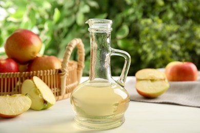 Photo of Natural apple vinegar and fresh fruits on white table against blurred background