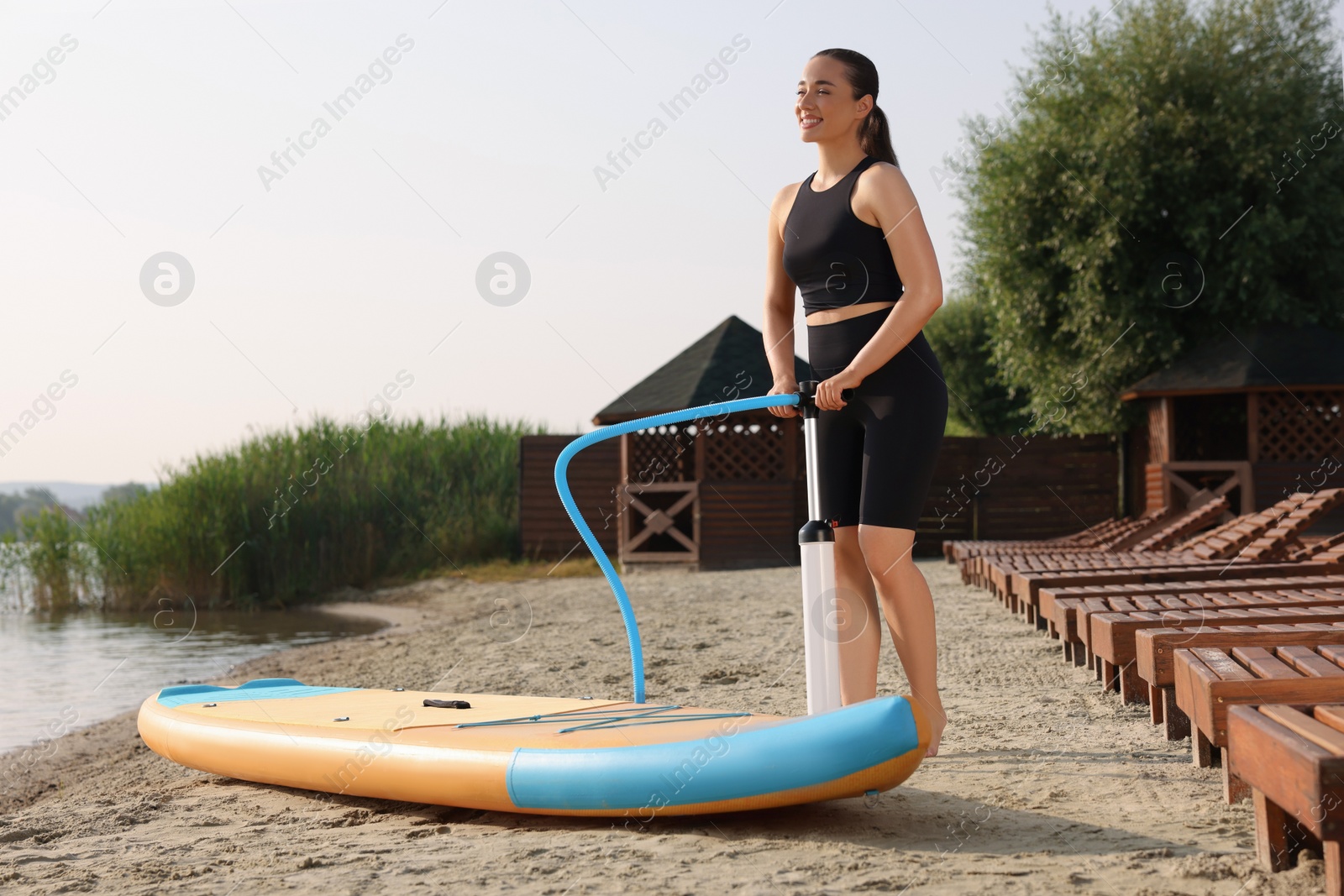 Photo of Woman pumping up SUP board on river shore