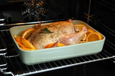 Chicken with orange slices baking in oven