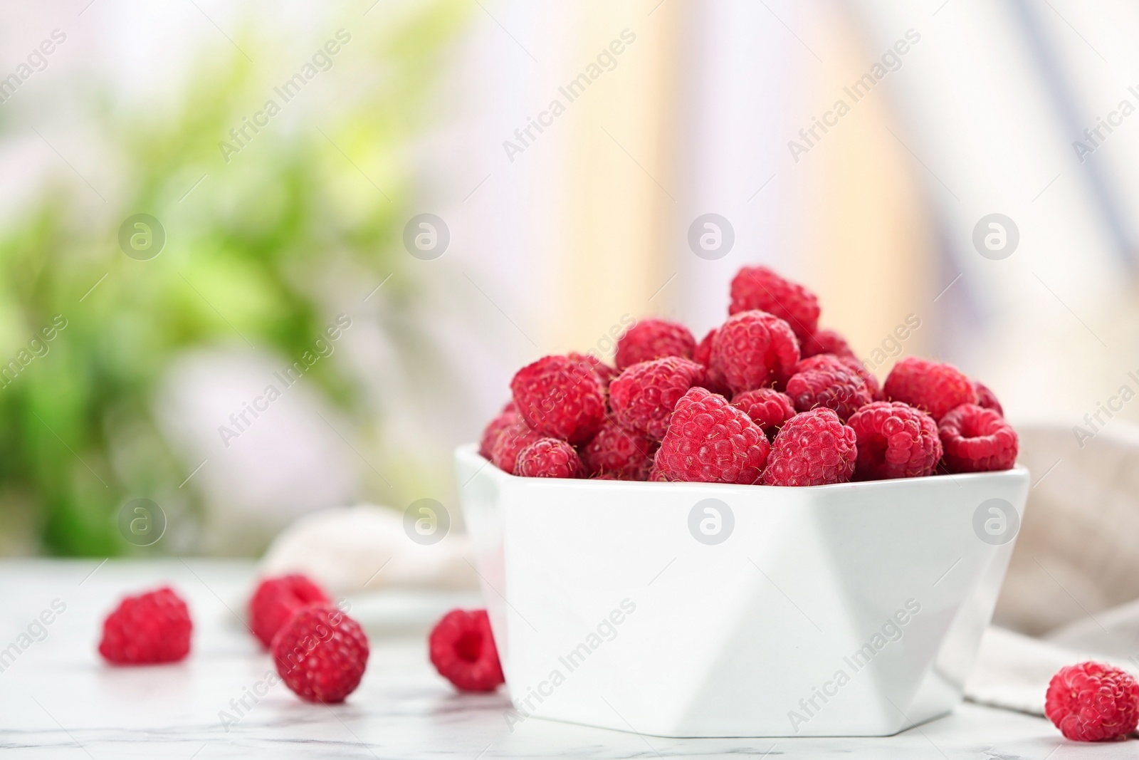 Photo of Bowl with ripe aromatic raspberries on table