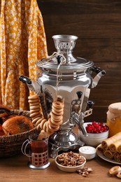 Photo of Traditional Russian samovar and treats on wooden table