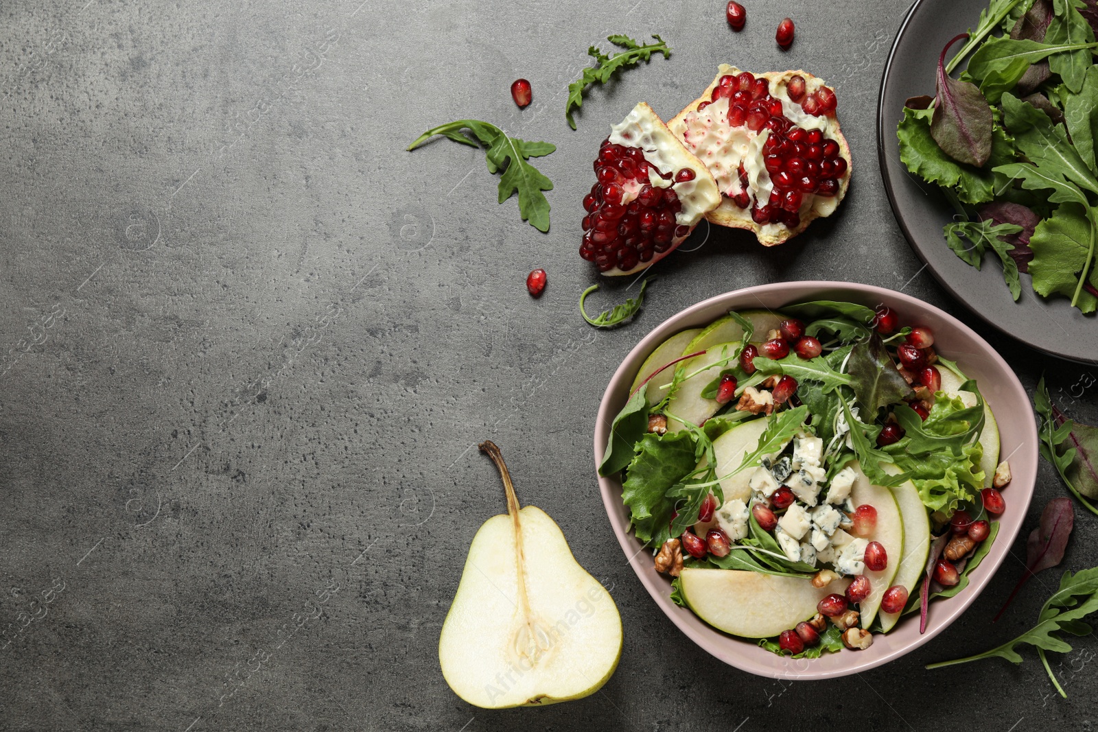 Photo of Tasty salad with pear slices and fresh ingredients on grey table, flat lay. Space for text