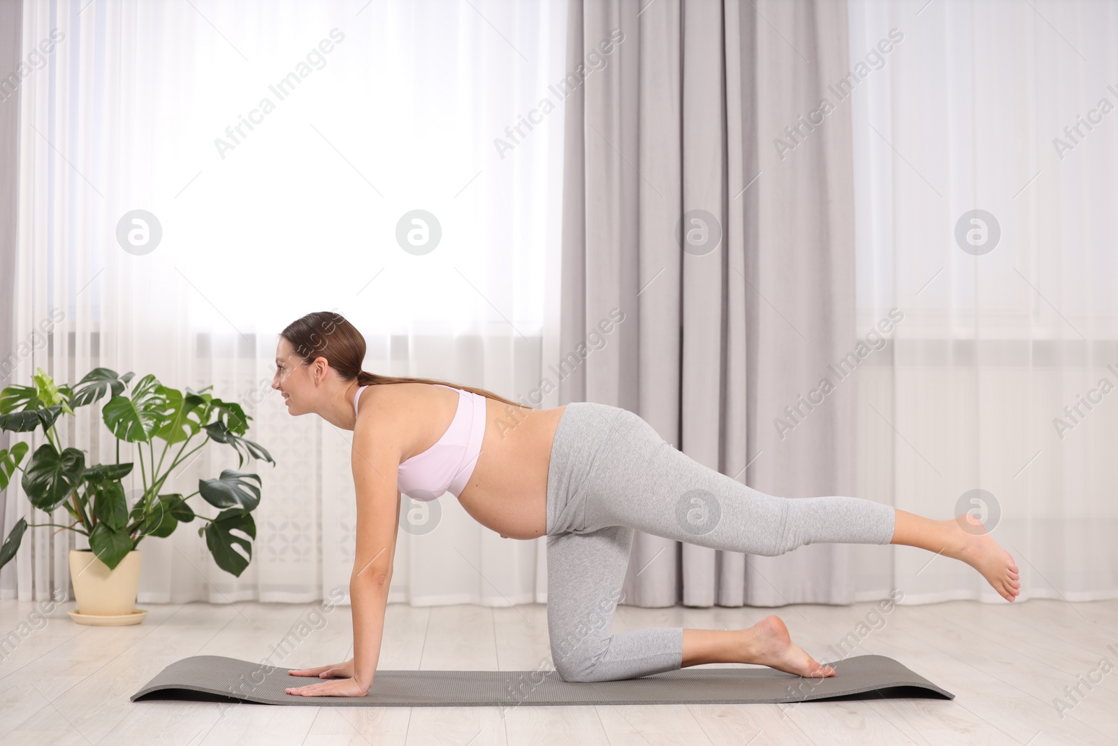 Photo of Pregnant woman doing exercises on yoga mat at home