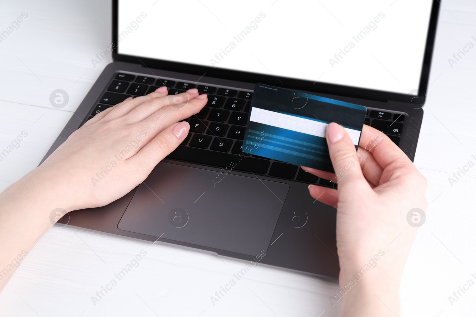 Photo of Online payment. Woman with laptop and credit card at white table, closeup