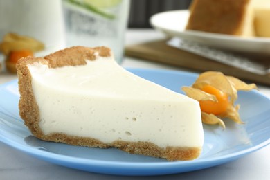 Piece of tasty vegan tofu cheesecake and physalis fruit on table, closeup