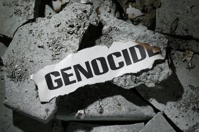 Photo of Paper with word Genocide on pieces of concrete, top view