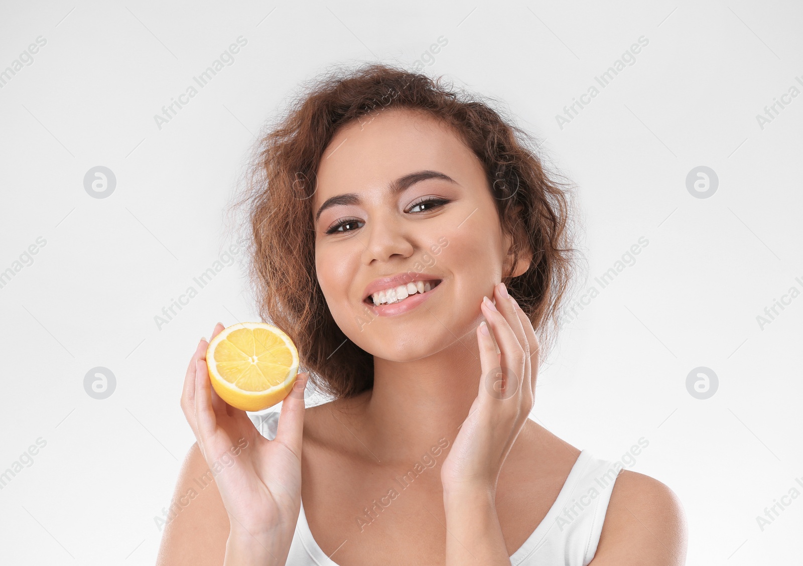 Photo of Beautiful young woman with acne problem holding lemon on light background. Skin allergy