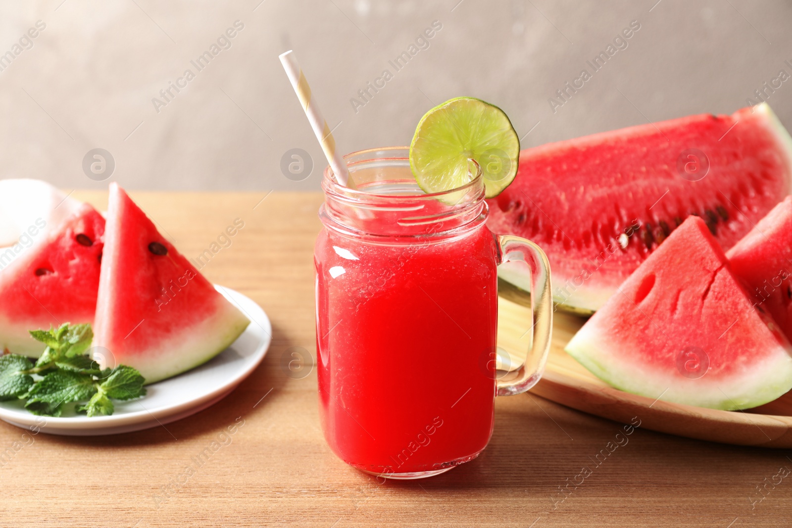 Photo of Summer watermelon drink in mason jar and sliced fruit on table