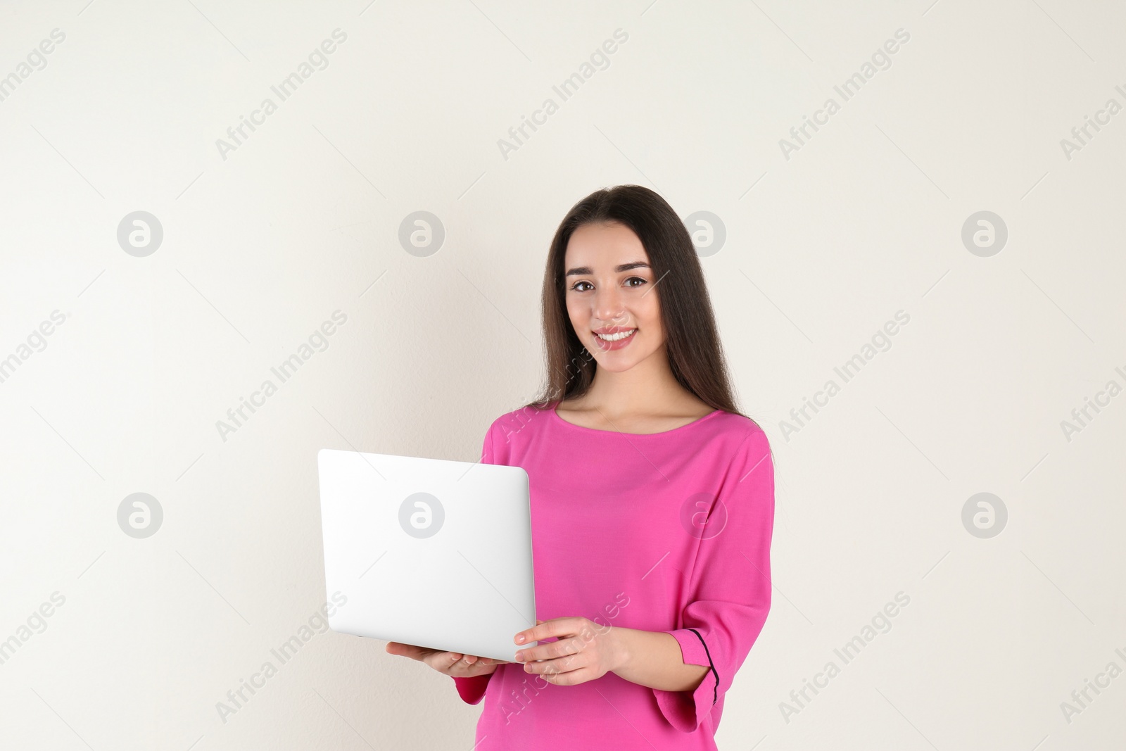 Photo of Portrait of young woman in casual outfit with laptop on light background