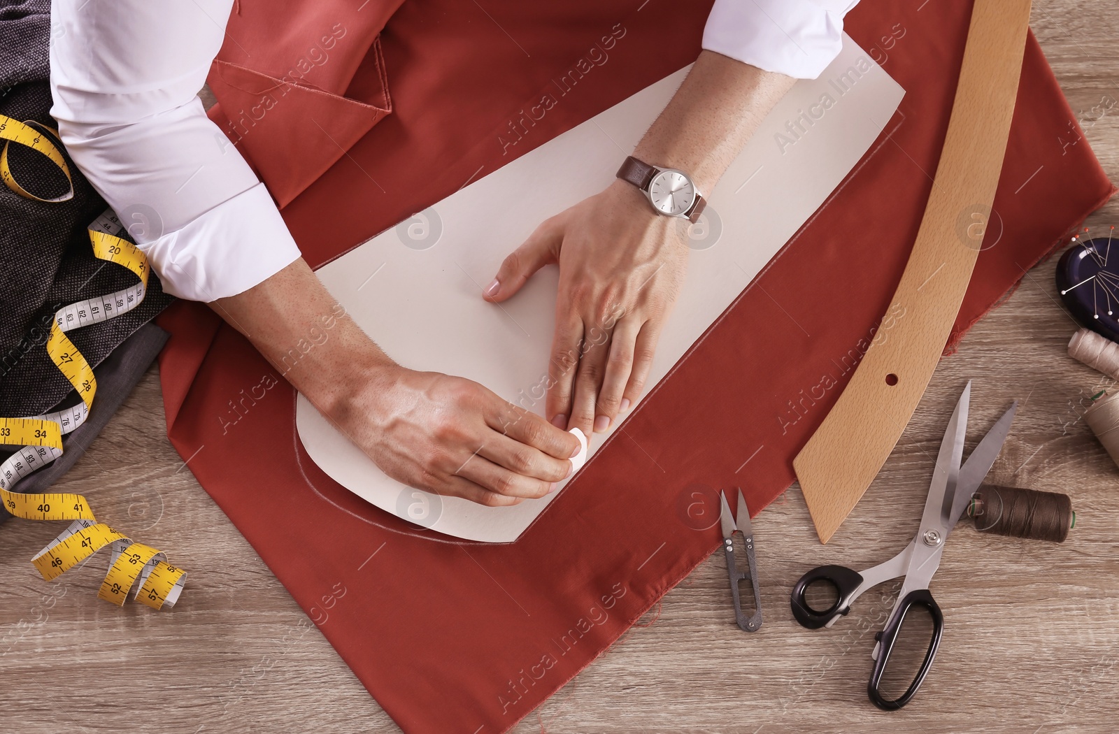 Photo of Tailor working with cloth at table in atelier, top view