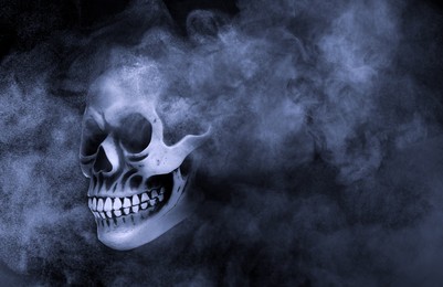 Image of Scary skull emerging from smoke in darkness