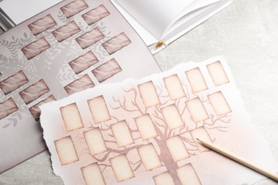 Photo of Blank family tree charts, notebook and pencil on grey table, closeup