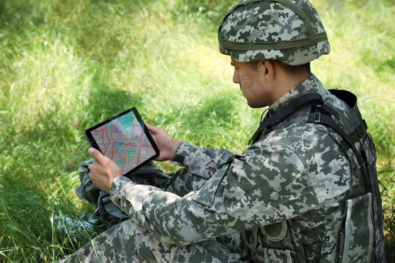 Photo of Soldier with backpack using tablet in forest