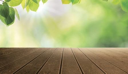 Image of Empty wooden surface and beautiful green leaves on blurred background. Bokeh effect