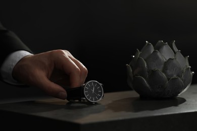 Man putting luxury wrist watch on table, closeup