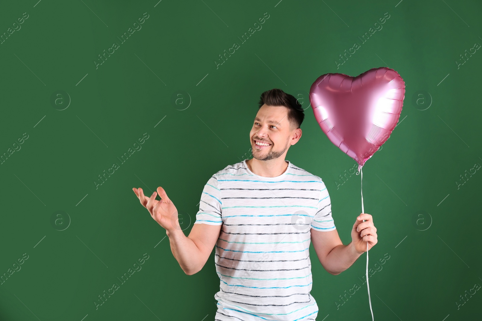 Photo of Portrait of young man with heart shaped balloon on color background