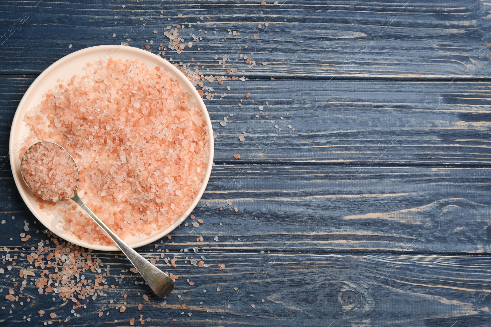 Photo of Pink himalayan salt on blue wooden table, flat lay. Space for text