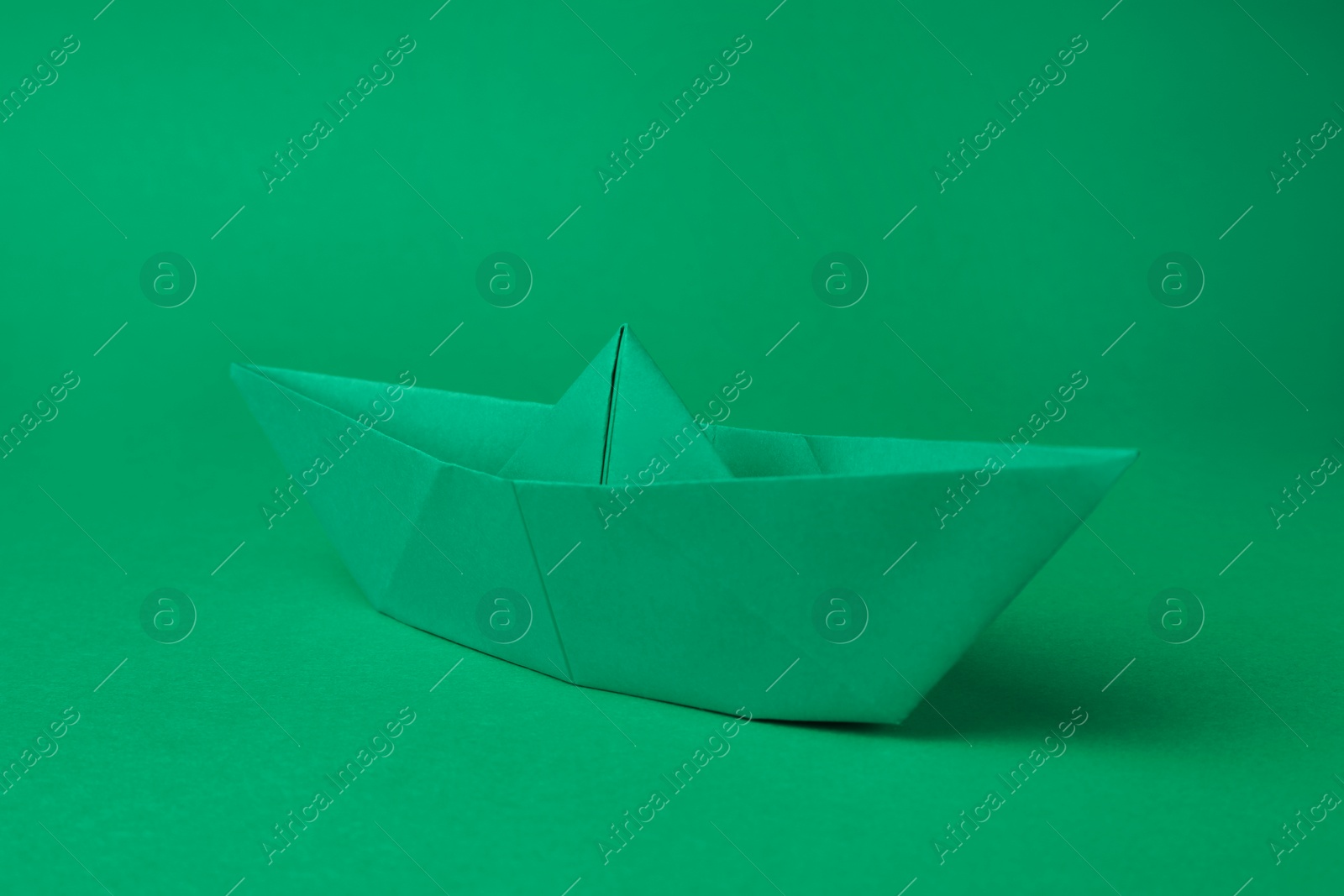 Photo of Origami art. Paper boat on green background