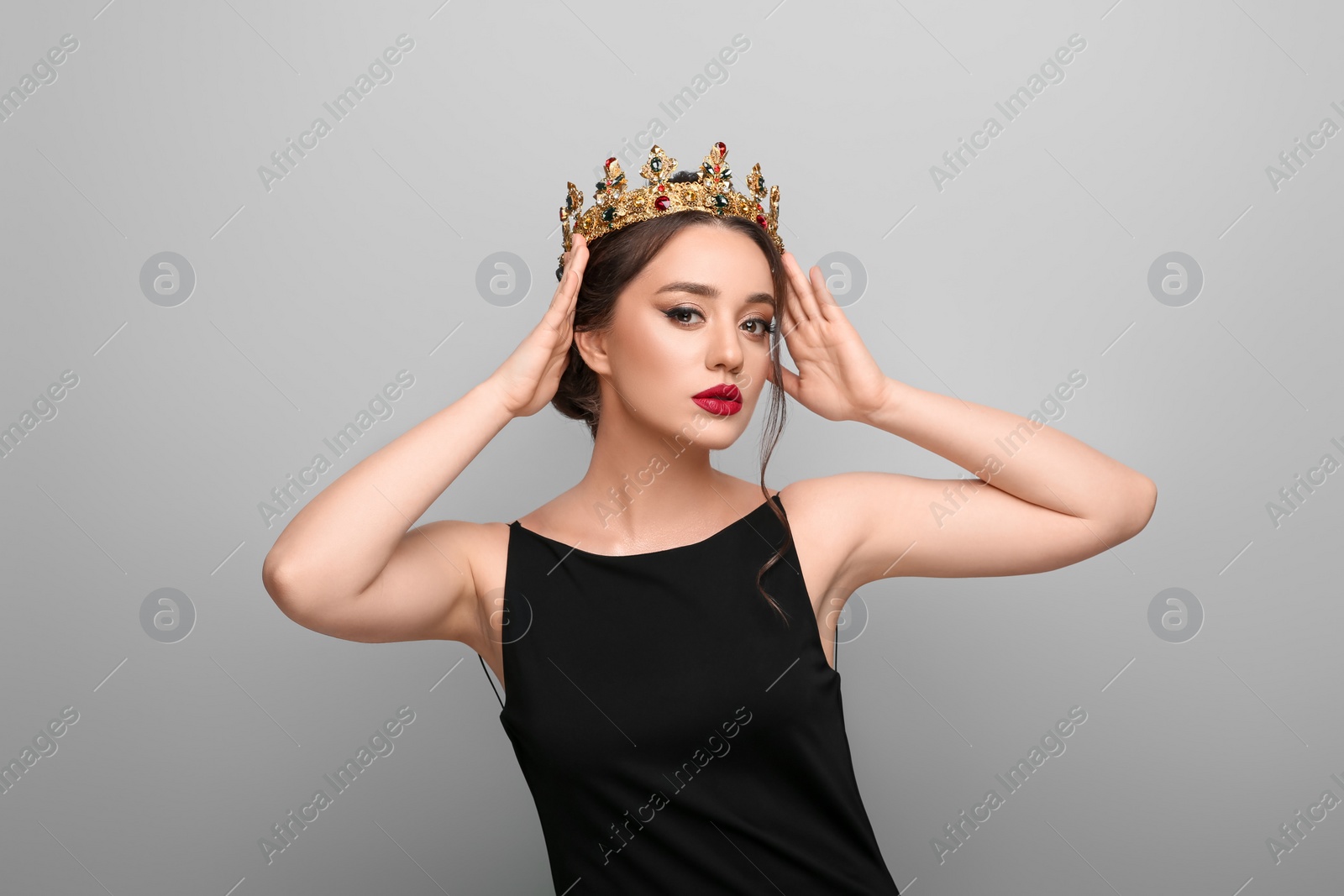 Photo of Beautiful young woman wearing luxurious crown on light grey background