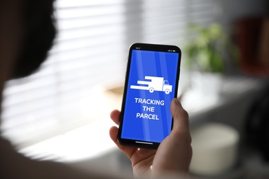 Image of Man tracking parcel via smartphone indoors, closeup