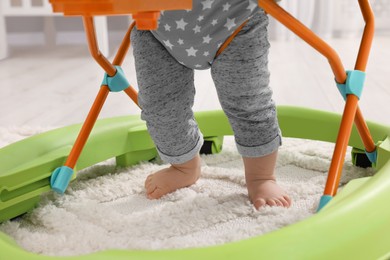 Photo of Little baby making first steps with toy walker on carpet indoors, closeup