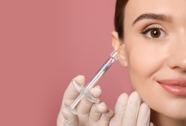 Photo of Beautiful woman getting facial injection on pink background, closeup. Cosmetic surgery