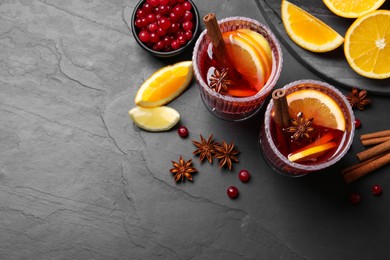 Photo of Aromatic punch drink and ingredients on black table, flat lay. Space for text