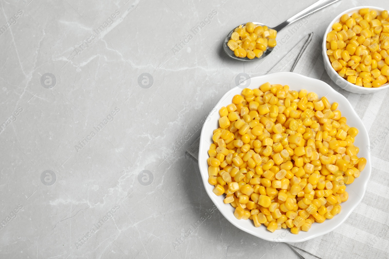 Photo of Delicious canned corn in bowl on marble table, flat lay. Space for text