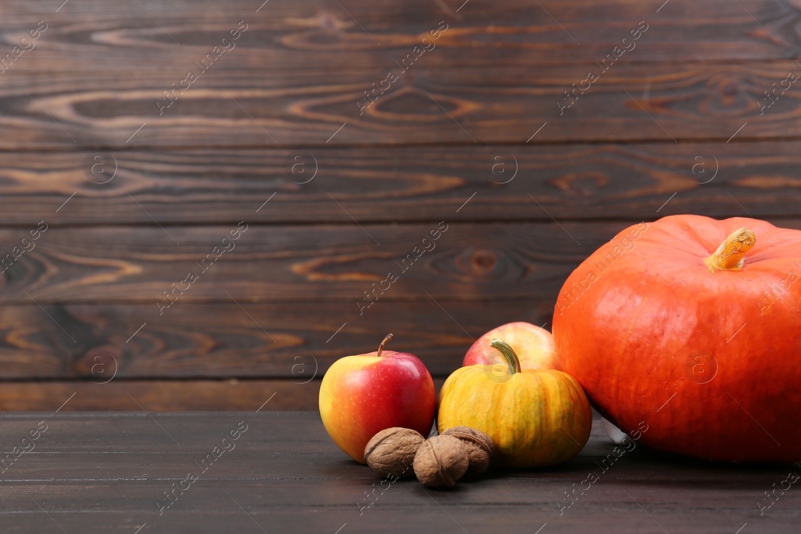 Photo of Happy Thanksgiving day. Fresh pumpkins, walnuts and apples on wooden table, space for text