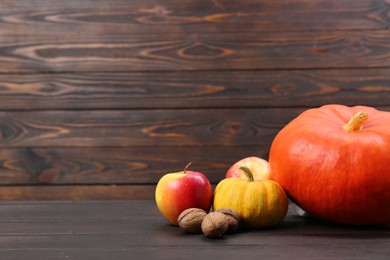 Photo of Happy Thanksgiving day. Fresh pumpkins, walnuts and apples on wooden table, space for text
