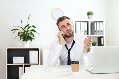 Lazy young man talking on smartphone in office