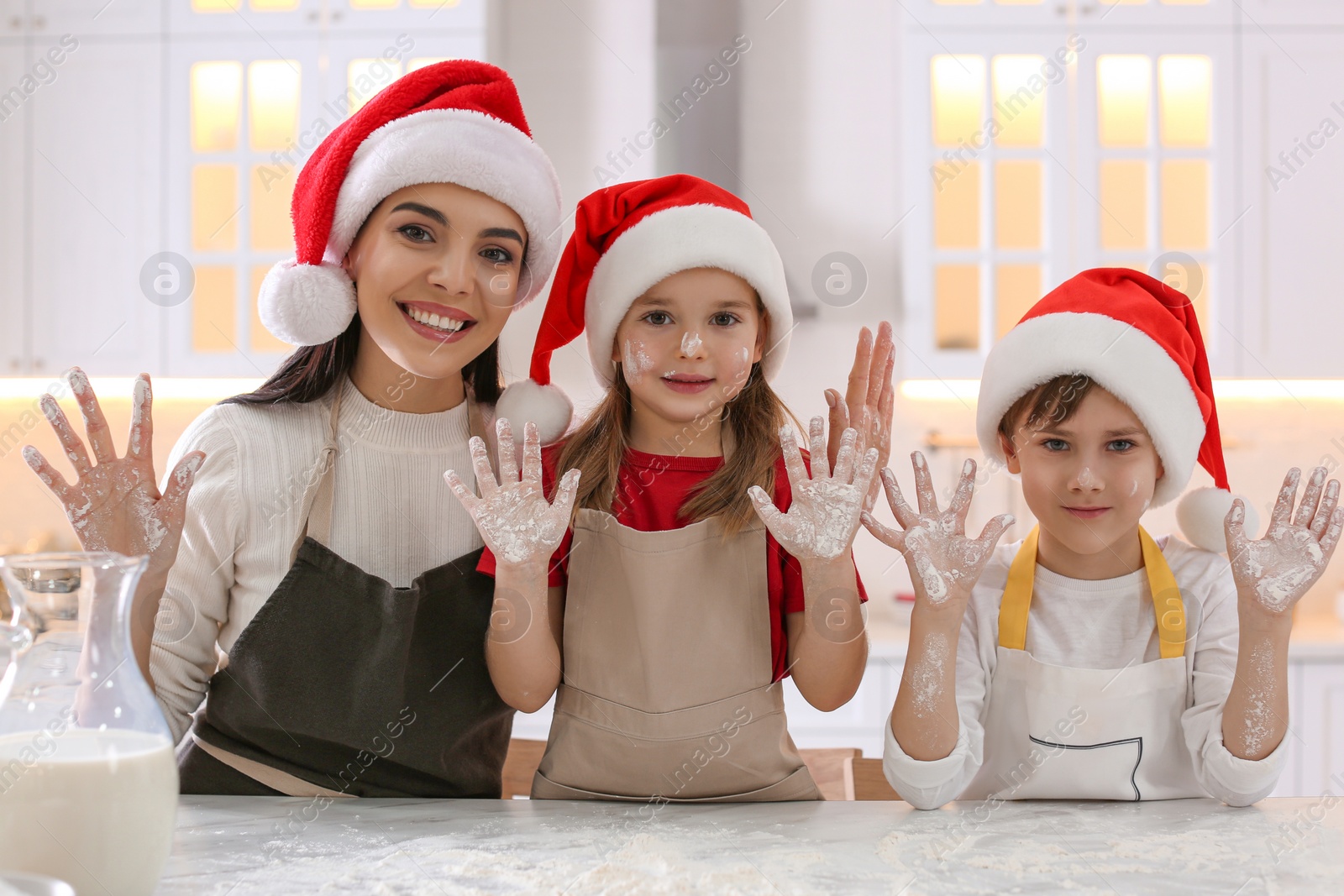 Photo of Mother and her cute little children having fun while making Christmas cookies in kitchen