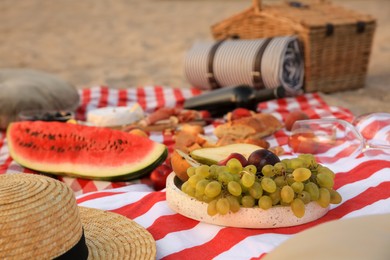 Different tasty snacks on picnic blanket outdoors