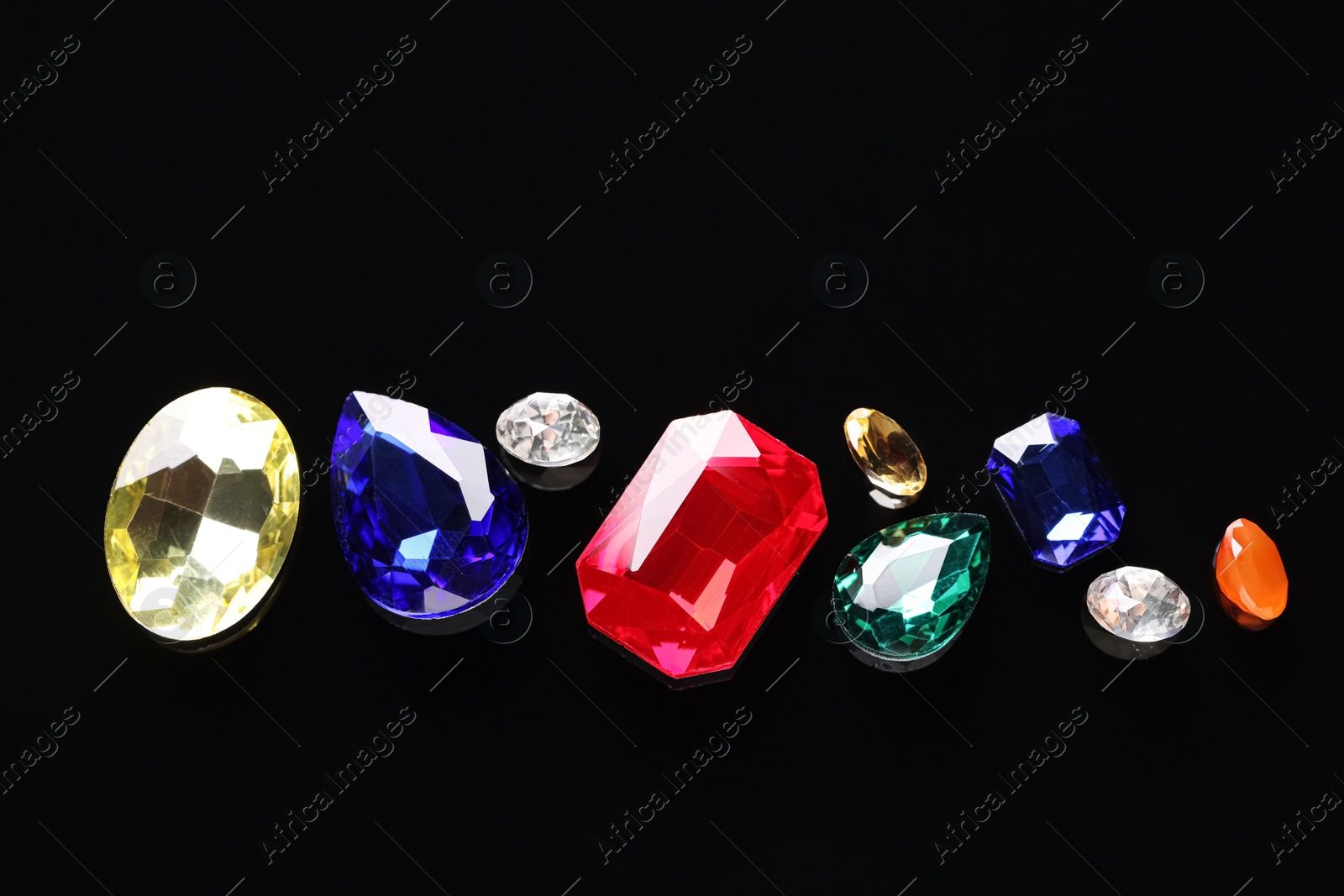 Photo of Different beautiful gemstones for jewelry on black background, flat lay