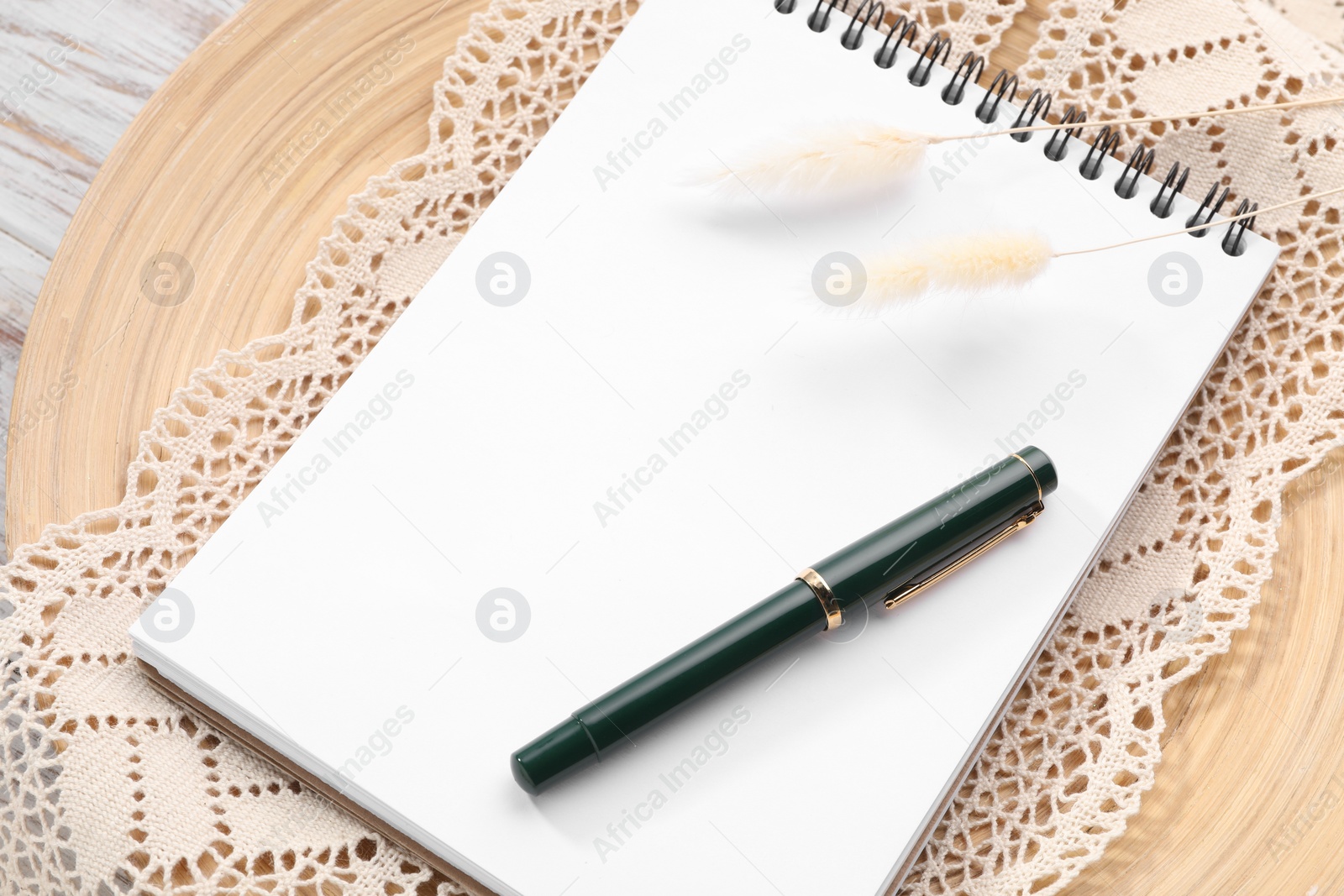 Photo of Guest list. Notebook, pen, spikelets and lace ribbon on wooden board, above view