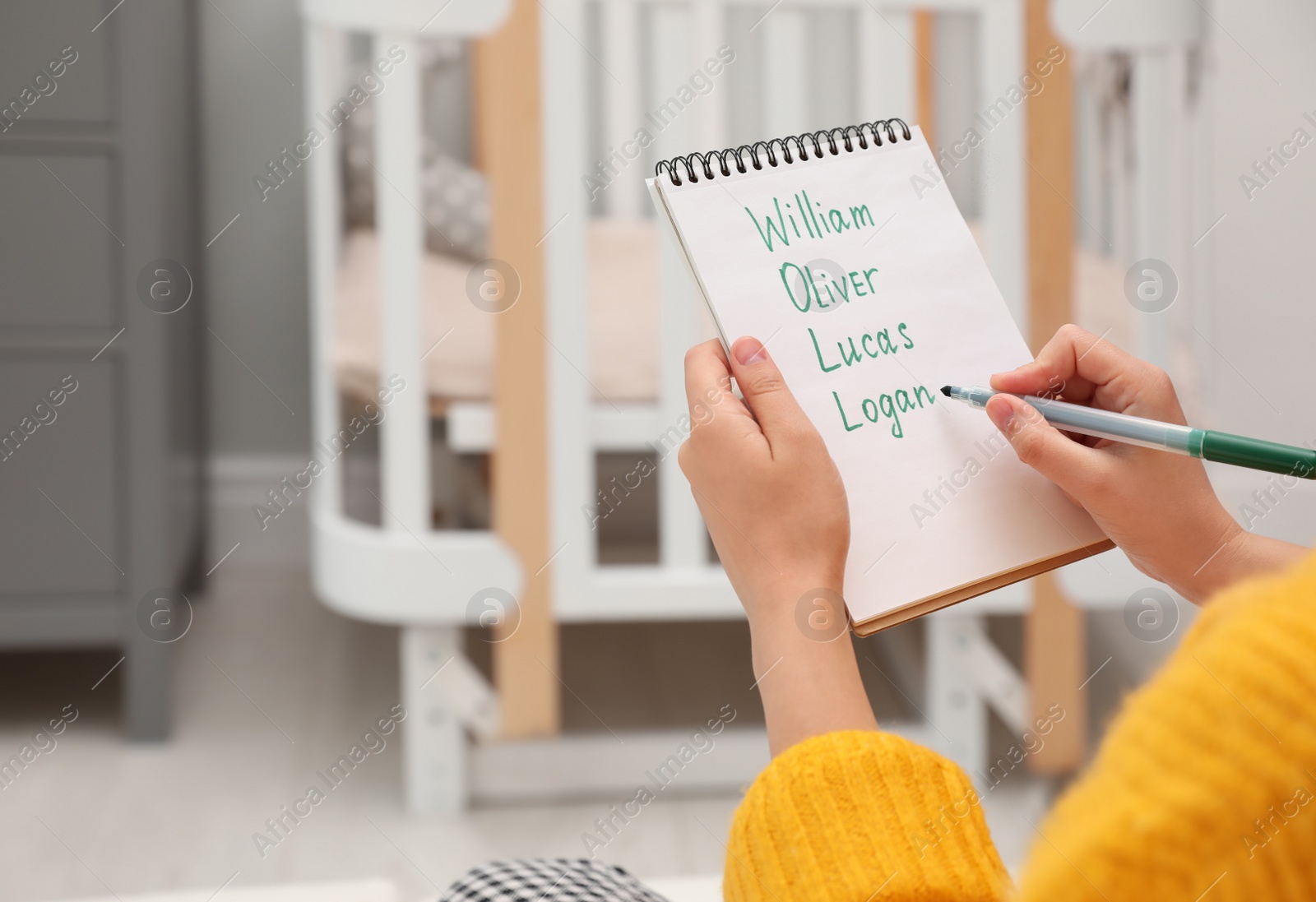 Photo of Pregnant woman with baby names list sitting indoors, closeup