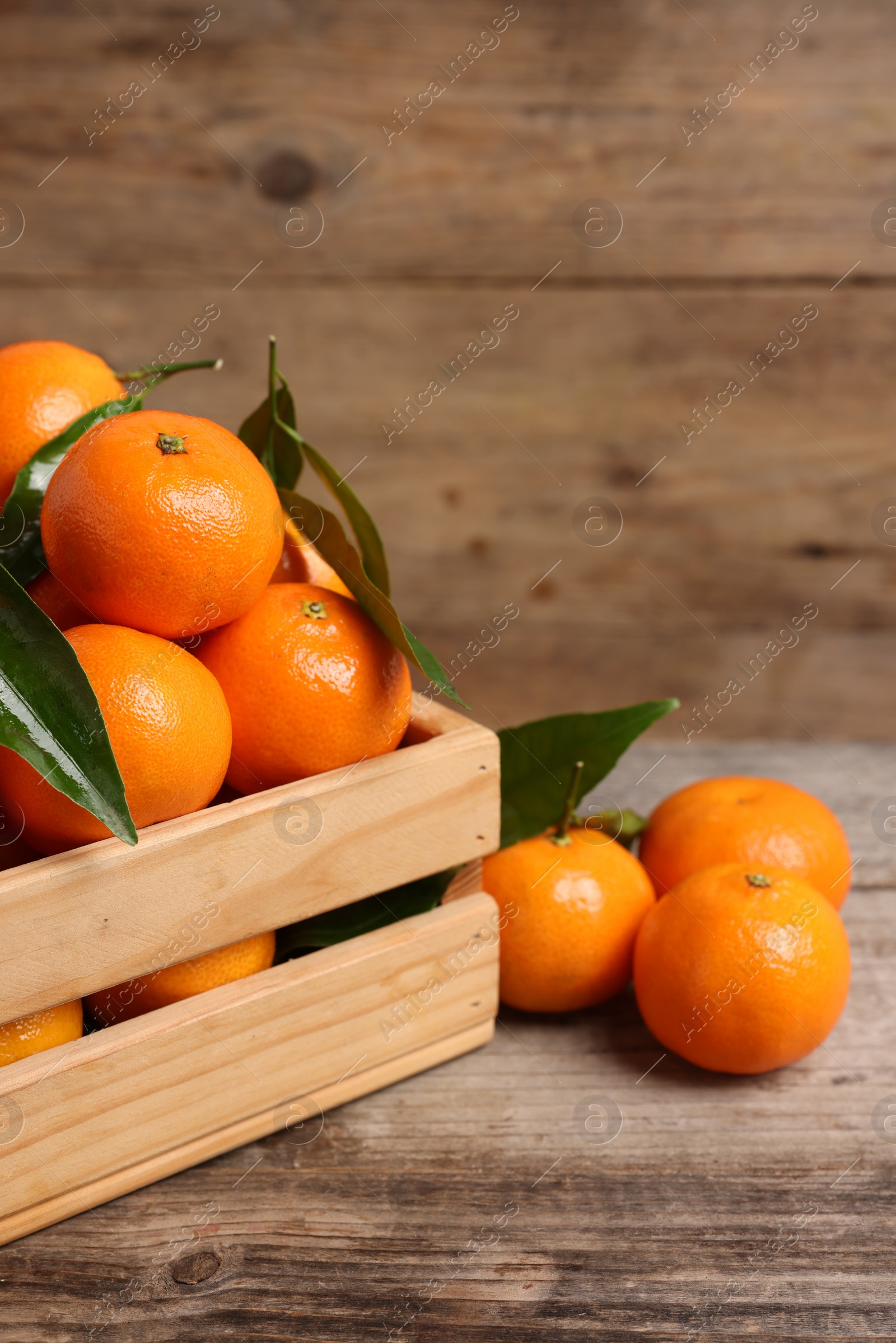 Photo of Delicious tangerines with leaves on wooden table. Space for text