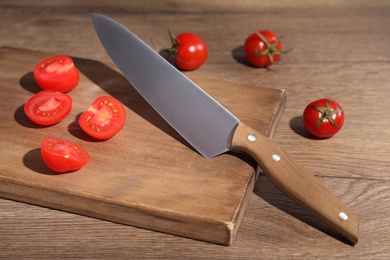 Chef knife and fresh tomatoes on wooden table. Clean dishes