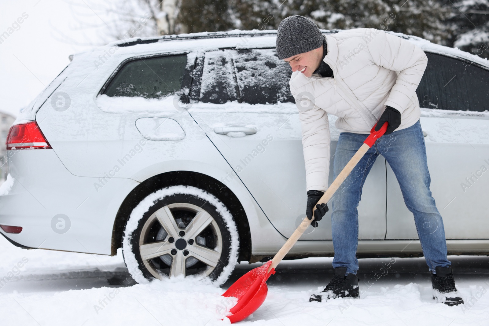 Photo of Man removing snow with shovel near car outdoors