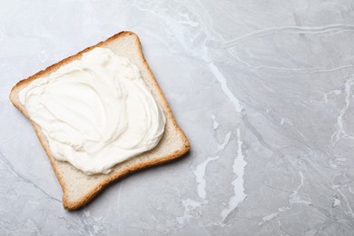 Photo of Slice of bread with tasty cream cheese on light grey marble table, top view. Space for text