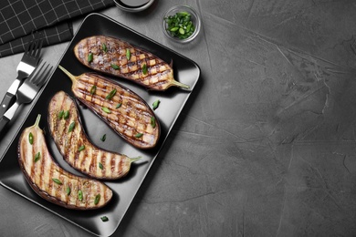 Delicious grilled eggplant halves served on grey table, flat lay. Space for text