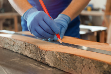 Photo of Professional carpenter making mark on wooden board in workshop, closeup