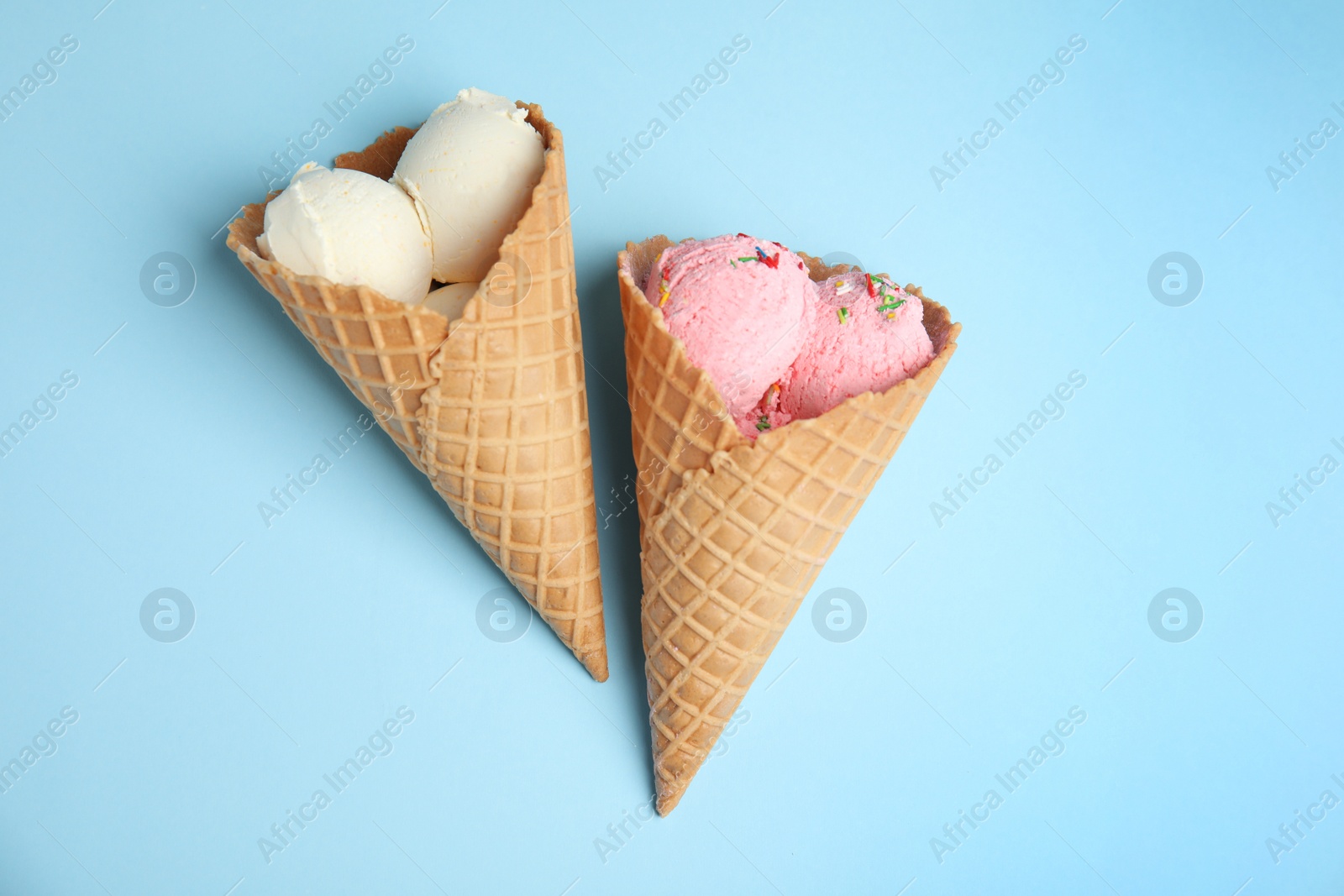 Photo of Delicious ice creams in wafer cones on blue background, flat lay
