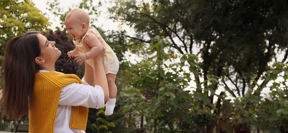 Happy mother with adorable baby walking in park on sunny day, space for text