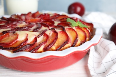 Delicious cake with plums on white wooden table, closeup